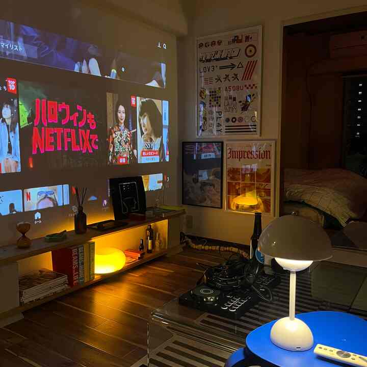 Warm wood tones and black accents characterize the living room with a projector screen and indirect lighting creating a cozy atmosphere