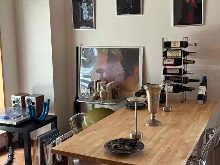 ナチュラルな色調の1LDKリビング、木製テーブルとワインラック、アートなオブジェが配置された雰囲気のある空間