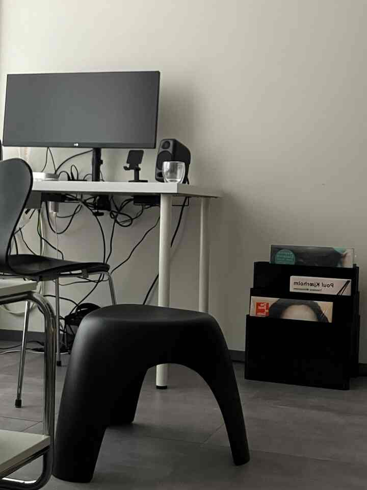 Monotone home office space in white and black featuring a stool and magazine rack with a simple, modern atmosphere
