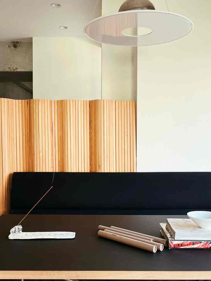 ナチュラルカラーと木目調が調和したダイニング、黒いソファと大きなペンダントライトが配置されたモダンな空間