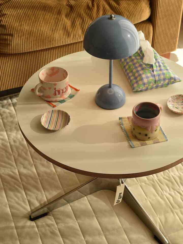 白い丸テーブルとライトブラウンのソファが配置された縦長のリビング、シンプルでナチュラルな雰囲気のインテリア