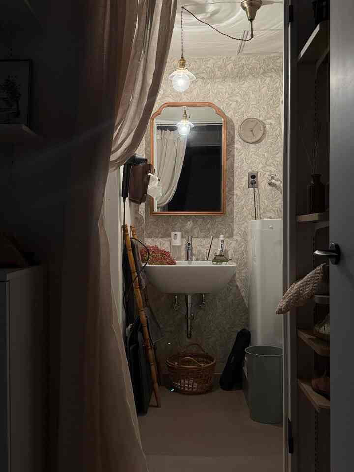 White-toned powder room with vintage patterned wallpaper and wood frame mirror, cozy and practical space