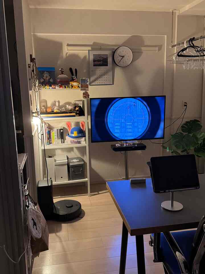 ホワイトとブラックのトーンが調和したコンパクトな一人暮らしのリビング、テレビ台とダイニングテーブルが配置された実用的な空間