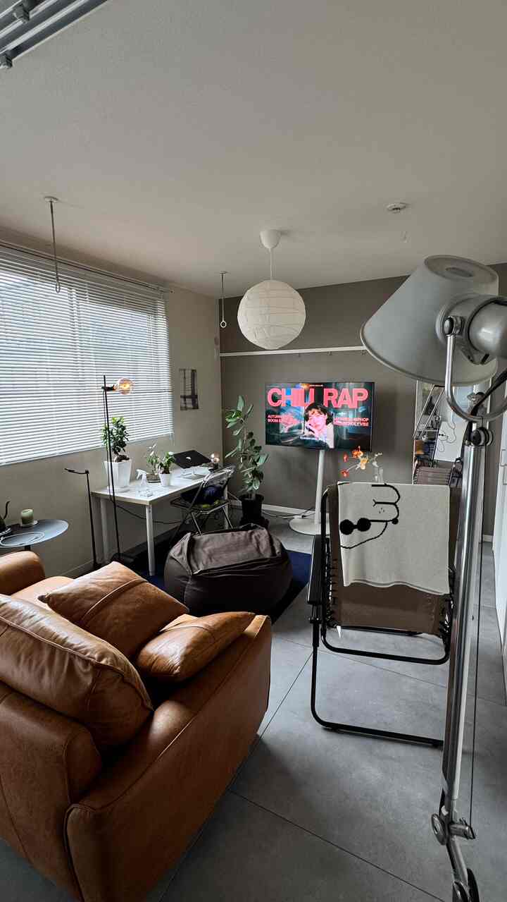 グレーとブラウンのトーンのワンルームリビング、レザーソファとホームオフィスデスクが配置された落ち着いたモダンな空間