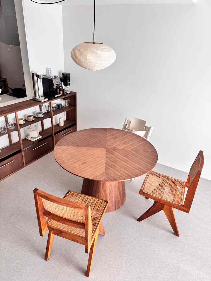 Natural wood tone and white round dining room featuring a pendant light and coffee equipment, creating a cozy home cafe atmosphere