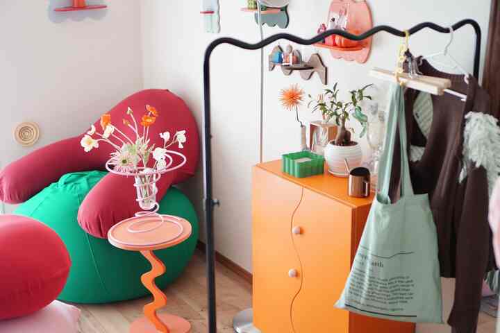 鮮やかなオレンジ色のキャビネットと赤・緑のビーズクッションが配置されたカラフルで居心地の良いリビングルーム