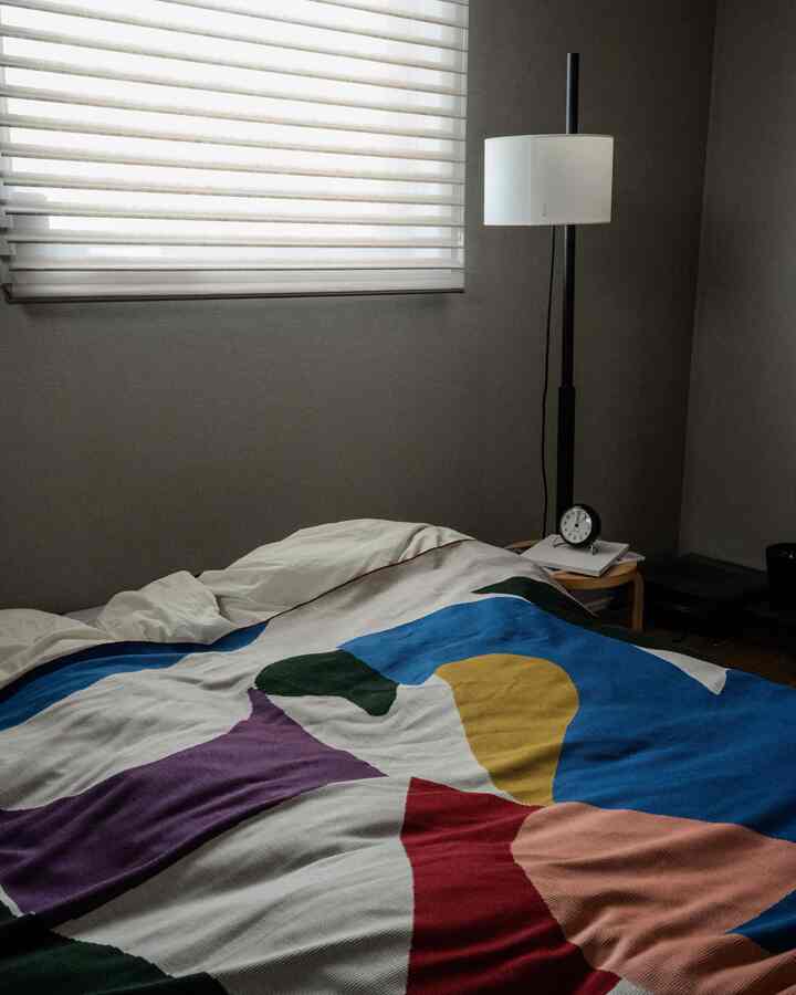 白と青を基調とした寝室、特徴的な模様のベッドカバーとフロアランプが配置された雰囲気のある空間