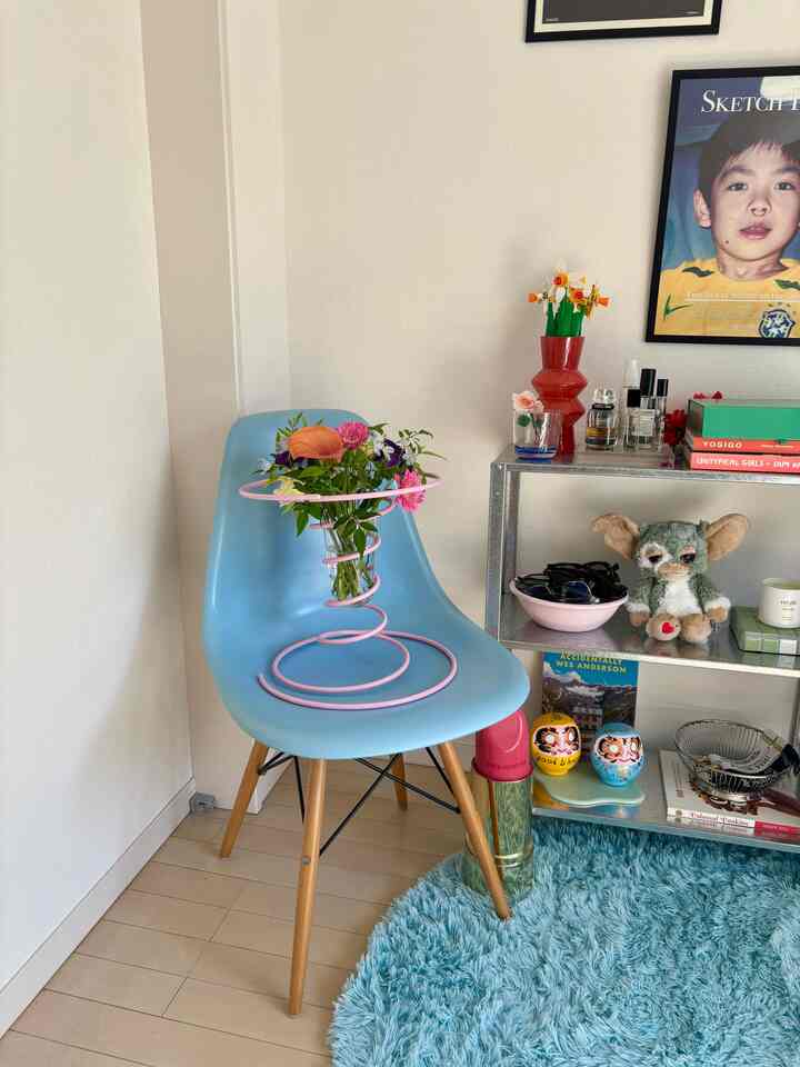 スカイブルーの色調が特徴の寝室の一角、青いチェアに花瓶とラグ、棚が配置された雰囲気のあるインテリア