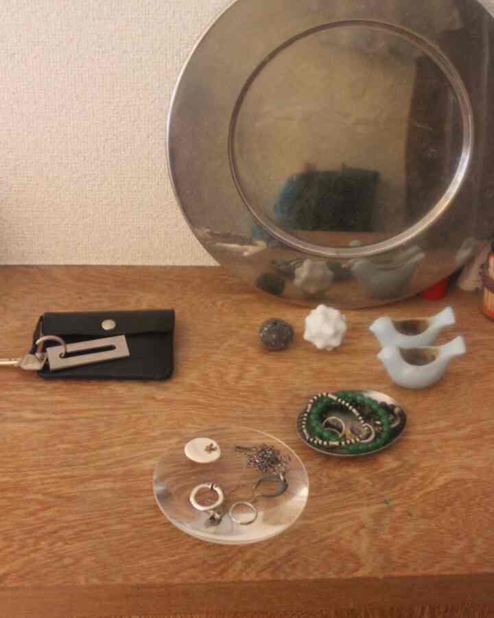 木目調の玄関テーブルにサービングプレートやトレイ、アクセサリーが置かれたミニマルな印象的な空間