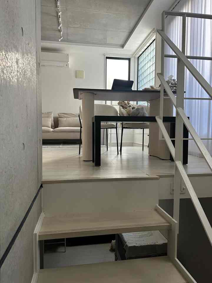 白とベージュのトーンの1LDKリビング、階段やダイニングテーブル、ソファが配置された落ち着いたモダンな空間