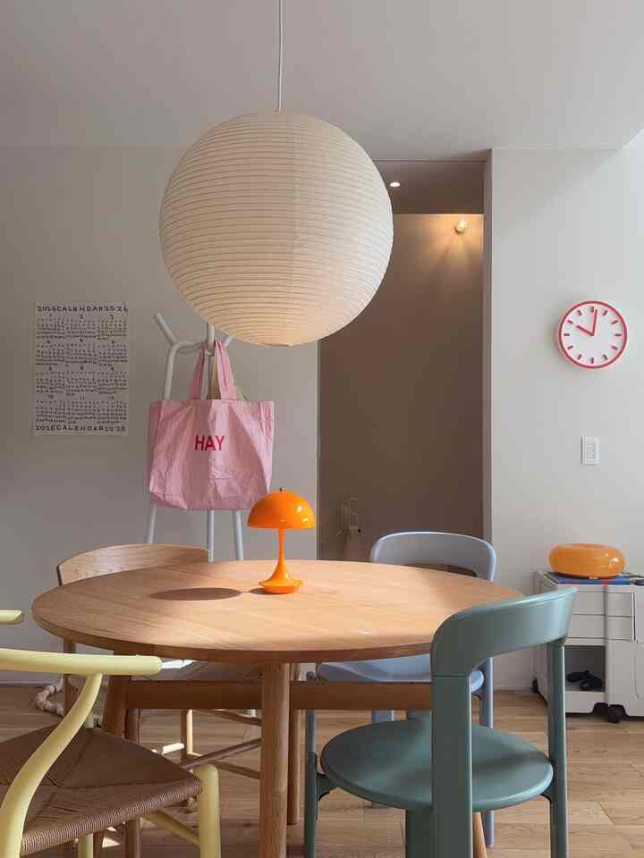 Natural toned dining room featuring a round wooden table, assorted chairs, and a white spherical pendant light creating a clean atmosphere