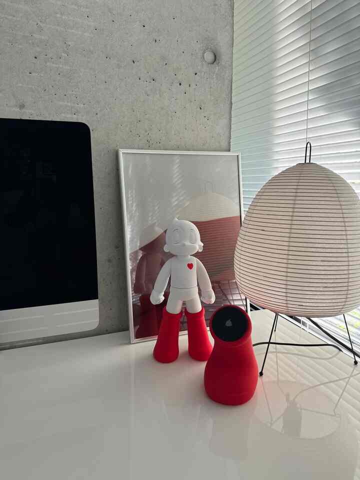 白と赤の調和が取れたモダンなデスク空間、アトムのフィギュアと照明が配置された印象的なインテリア