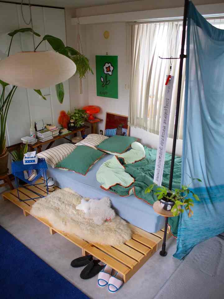 Natural style single household bedroom featuring blue and green bedding, pendant light, and plants creating a cozy atmosphere