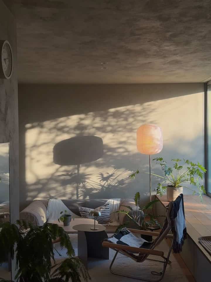 温かみのあるベージュ色調のリビング、ソファとサイドテーブル、フロアランプが配置された自然でモダンなインテリア