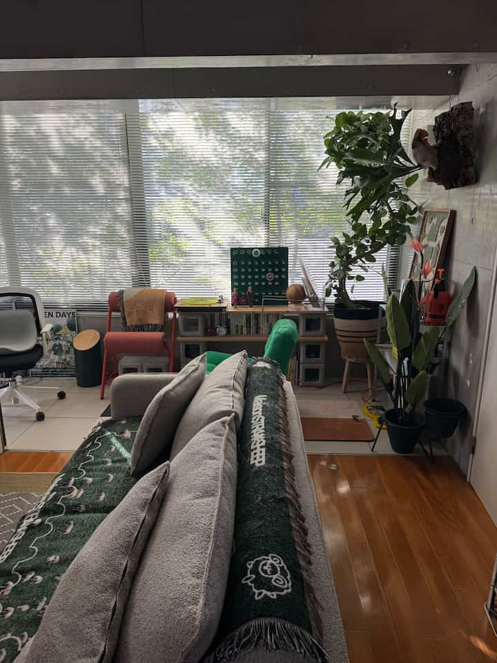 A living room with gray and wood tones featuring various plants and an armchair, creating a natural and cozy atmosphere