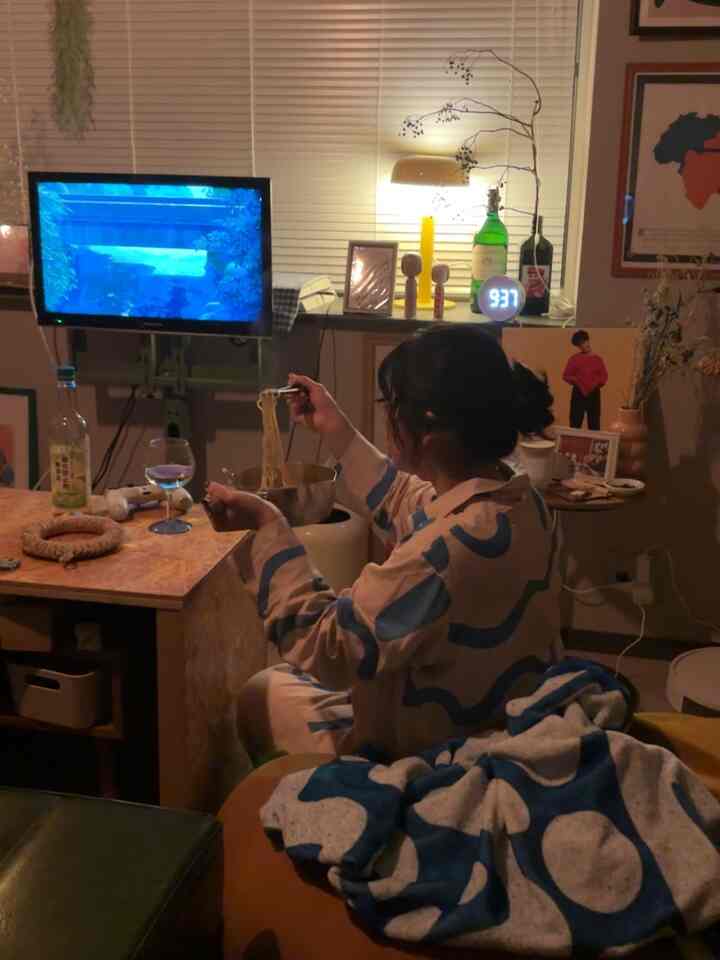 暖かいベージュと青の色調のワンルームリビング、テーブルランプとテレビが配置された居心地の良いインテリア