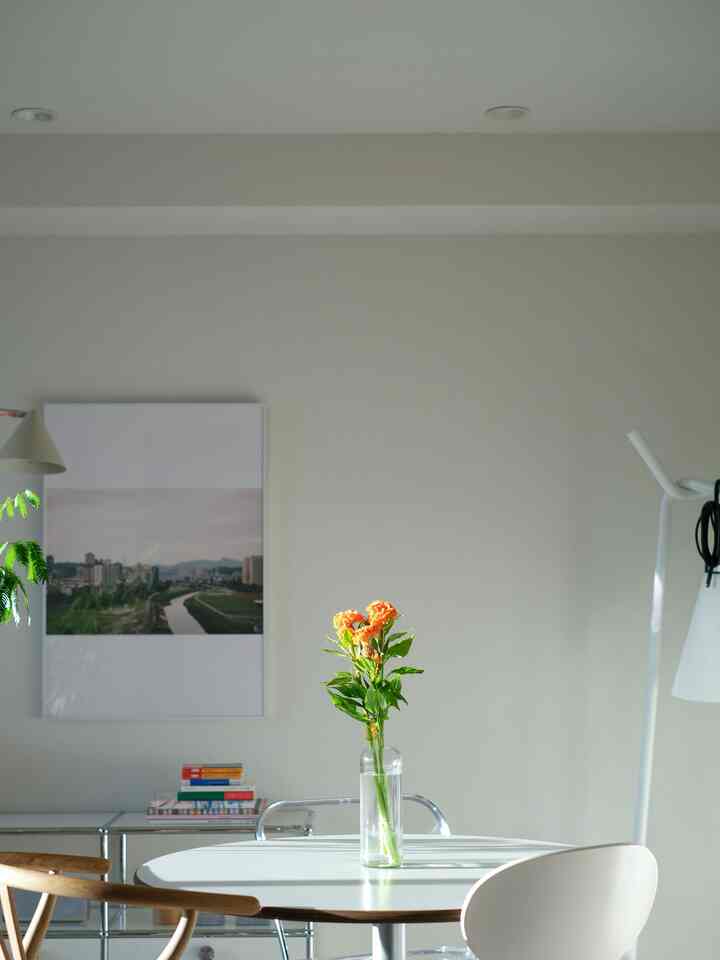 白とナチュラルトーンのダイニング、丸テーブルと花瓶が配置されたシンプルな雰囲気のあるインテリア