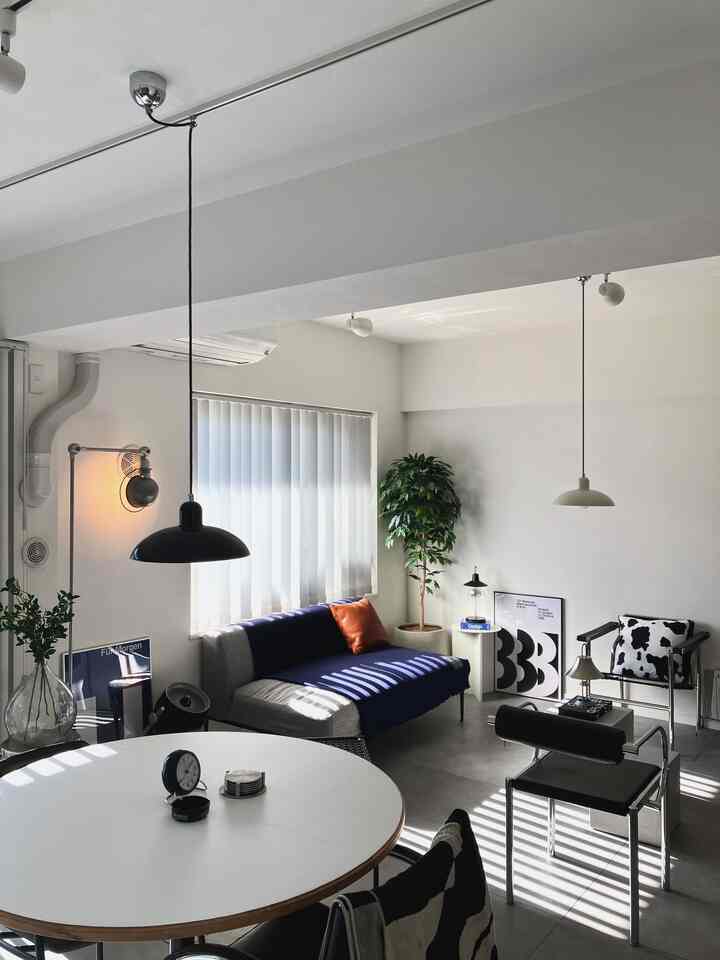 落ち着いたグレーとブラックの色調が特徴のダイニング、丸いダイニングテーブルとモダンなソファ、ペンダントライトが調和する印象的な空間