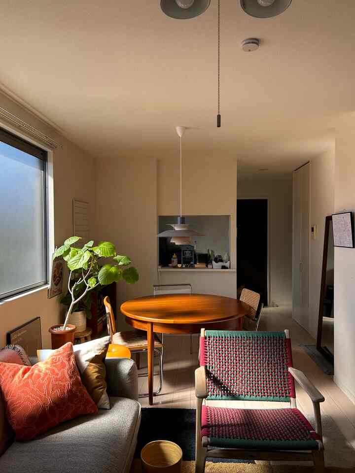 暖かいライトブラウンとナチュラルカラー調のミッドセンチュリーモダンなリビングとダイニングルーム、ラタンチェアとペンダントライトが印象的な空間