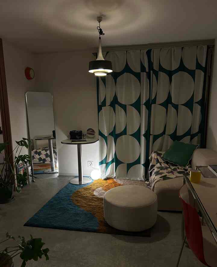 深いブルーとアイボリーのトーンが印象的な1LDKのリビング、丸テーブルとソファが配置された落ち着いた空間