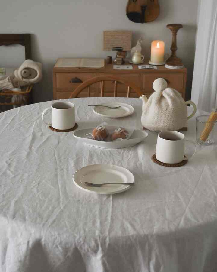 ナチュラルなブラウン家具とホワイトリネンのテーブルクロスが配されたダイニング、キャンドルが温かみのある雰囲気を演出する空間