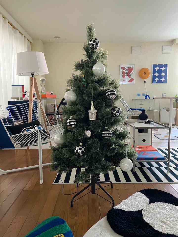 白と緑のトーンのリビング、中央にクリスマスツリーが配置され、モダンでミッドセンチュリー風の家具が温かみのある雰囲気を演出する印象的な空間