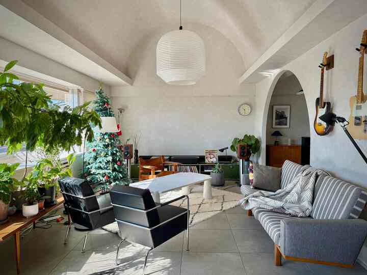 Natural tone living room featuring a Christmas tree, mid-century modern sofa and armchairs in a cozy space