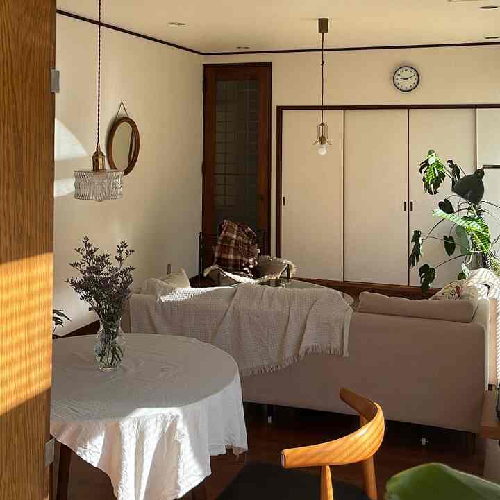 Natural living room with warm wood tones and white walls, featuring pendant lights and a round dining table creating a cozy atmosphere
