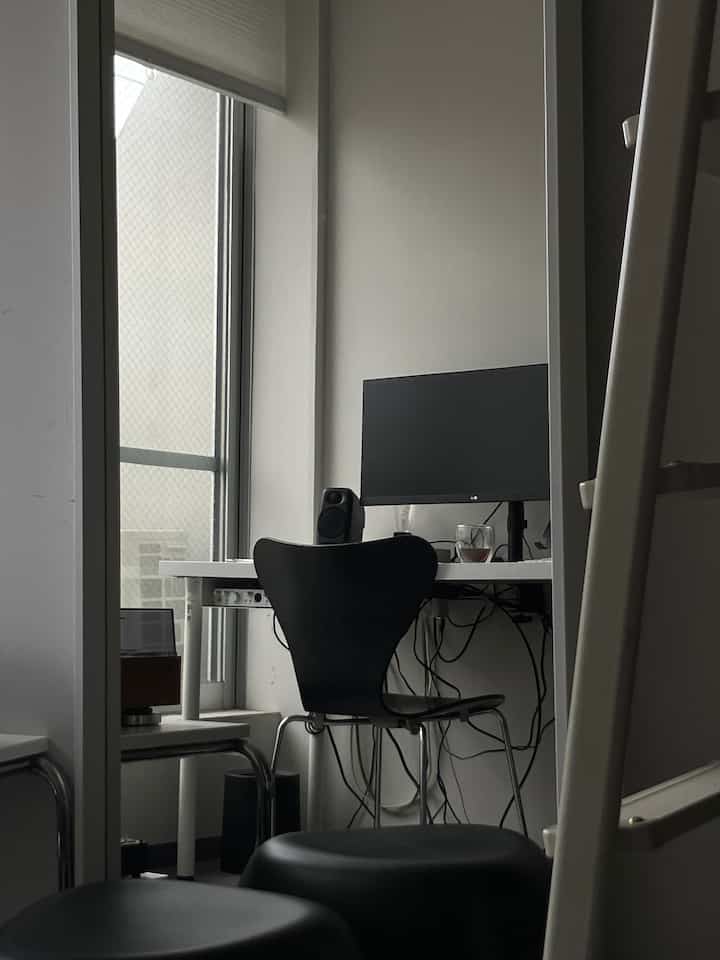 Monotone compact workspace featuring a black Series 7 chair and white desk with minimalistic design