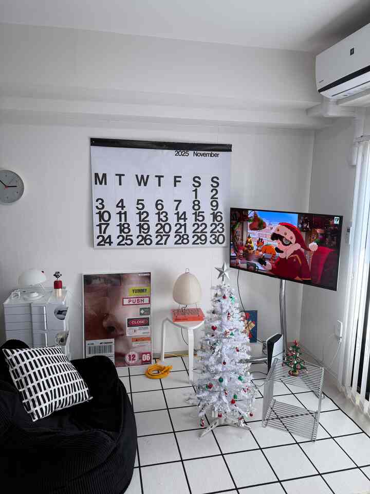 白と黒のモダンなリビングにクリスマスツリーとテレビが配置された、雰囲気のある空間