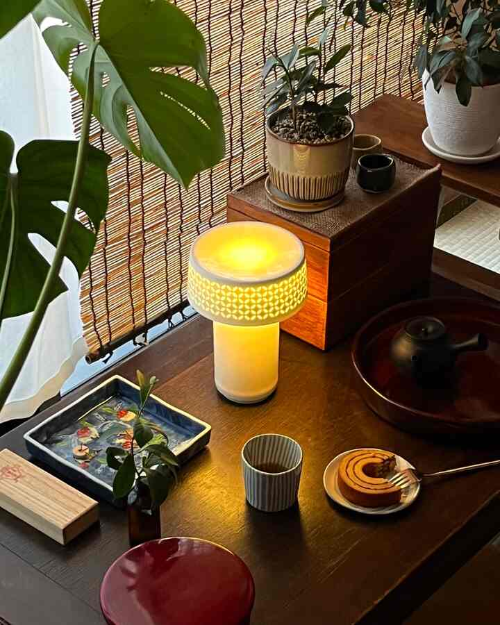 Natural brown wood-toned tea room space featuring warm lamp light and plants, creating a cozy atmosphere