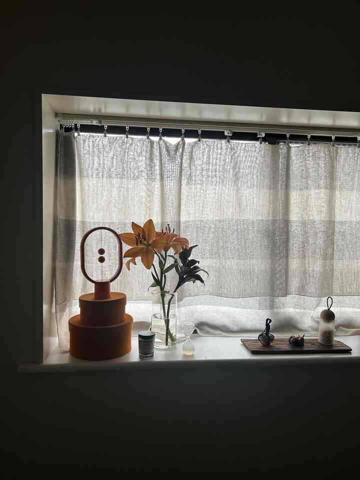 ナチュラルカラーのベージュ調ワンルームの出窓、花瓶やキャンドル、オブジェが配置されたシンプルなインテリア