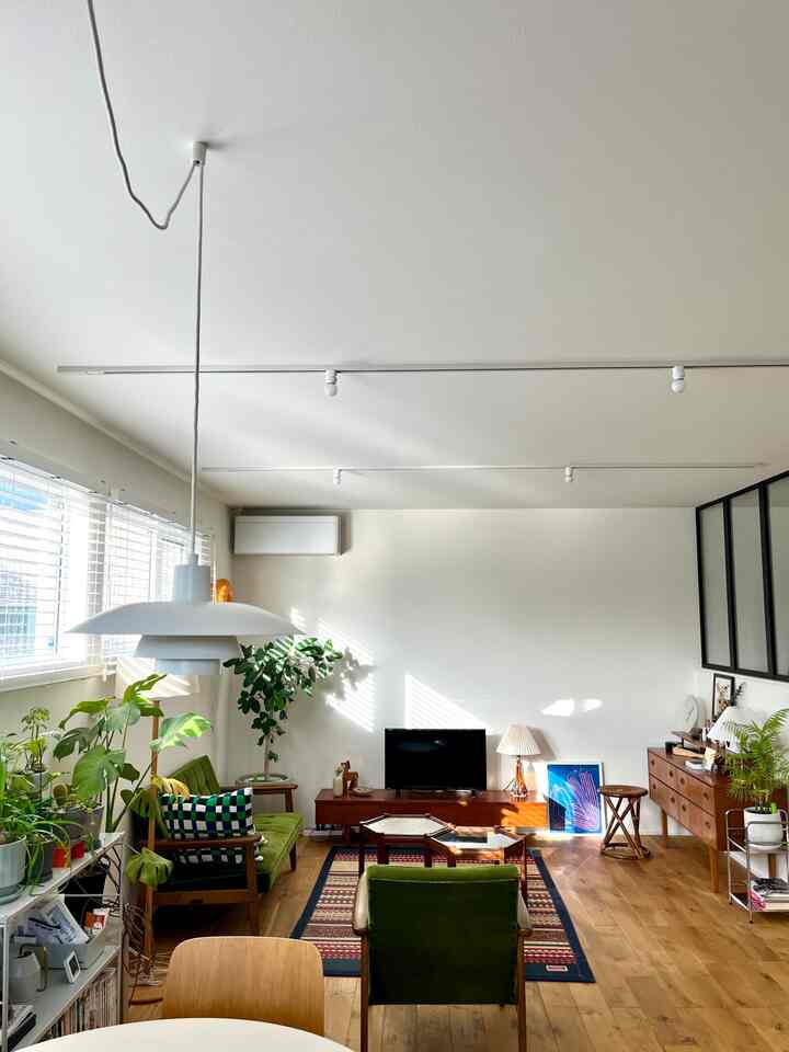 暖かい木目調とナチュラルなグリーンの植物が配置されたミッドセンチュリーモダンのリビング