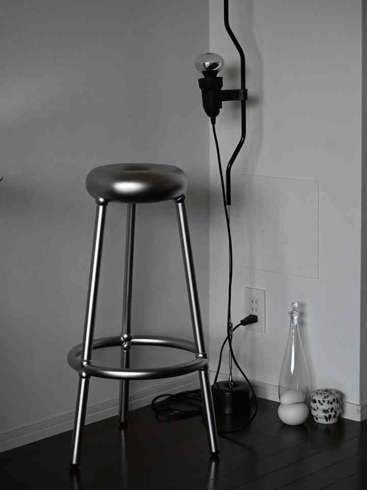 シルバー色調のモダンなキッチンの一角、金属製スツールとペンダントライトが配置された印象的な空間