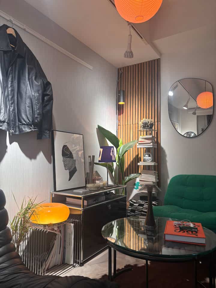 Natural-toned 8-tatami living room with green sofa and wood panel, featuring plants and sideboard in a modern, warm atmosphere