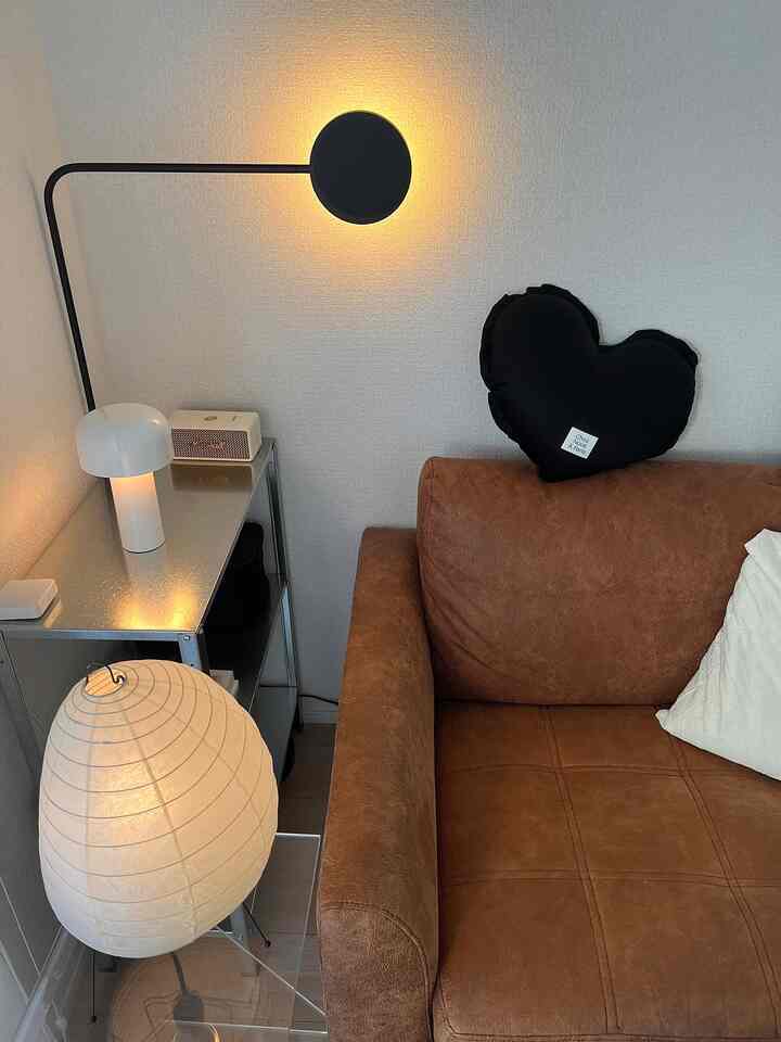 暖かい黄色の間接照明があるモダンな1LDKリビング、ブラウンのソファと金属の棚が配置された落ち着いた空間