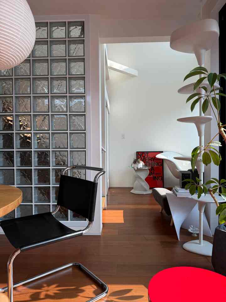 温かみのある木目調と白を基調としたミッドセンチュリーモダンのリビング、ヴィンテージサイドテーブルの上でくつろぐ猫がいる印象的な空間