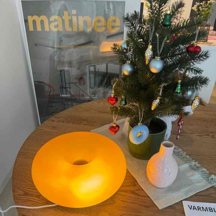 暖かいオレンジ色の光とナチュラルウッド調の1LDKダイニングスペース、小さなクリスマスツリーと照明が調和する雰囲気のあるインテリア