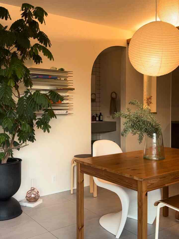 暖かみのある木目調と白が調和したダイニング、植物とペンダントライトが印象的な空間