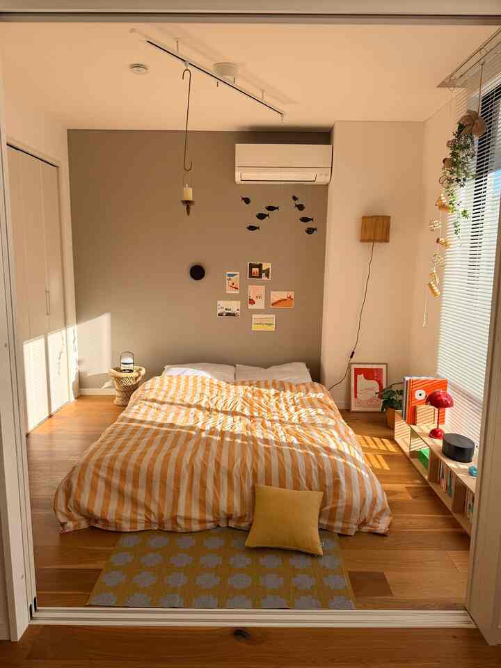 暖かいイエローとオレンジの色調の寝室、中央にベッドと寝具が配置された北欧風の雰囲気あるインテリア