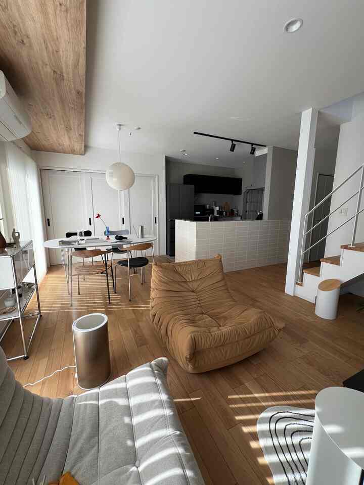 Modern and natural living room and kitchen space in white and brown tones, featuring cozy furniture and lighting