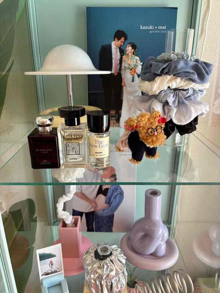 A mint green and lavender toned display shelf in living room featuring perfumes, decorative objects, and scrunchies arranged neatly in a cozy space