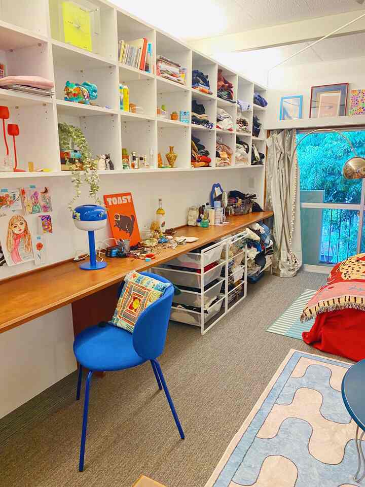 Natural colors combined with blue accents define this small single household bedroom-style home office, featuring a long desk and shelving