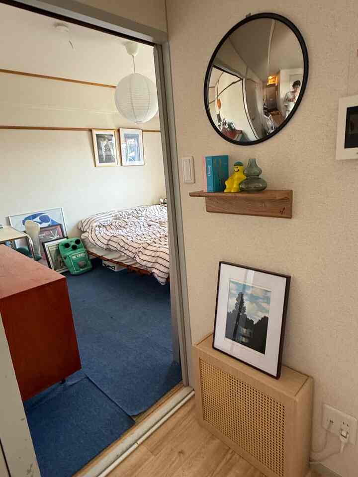 Blue carpet and orange-toned wood furniture in a two-person household bedroom viewed from the living room entrance