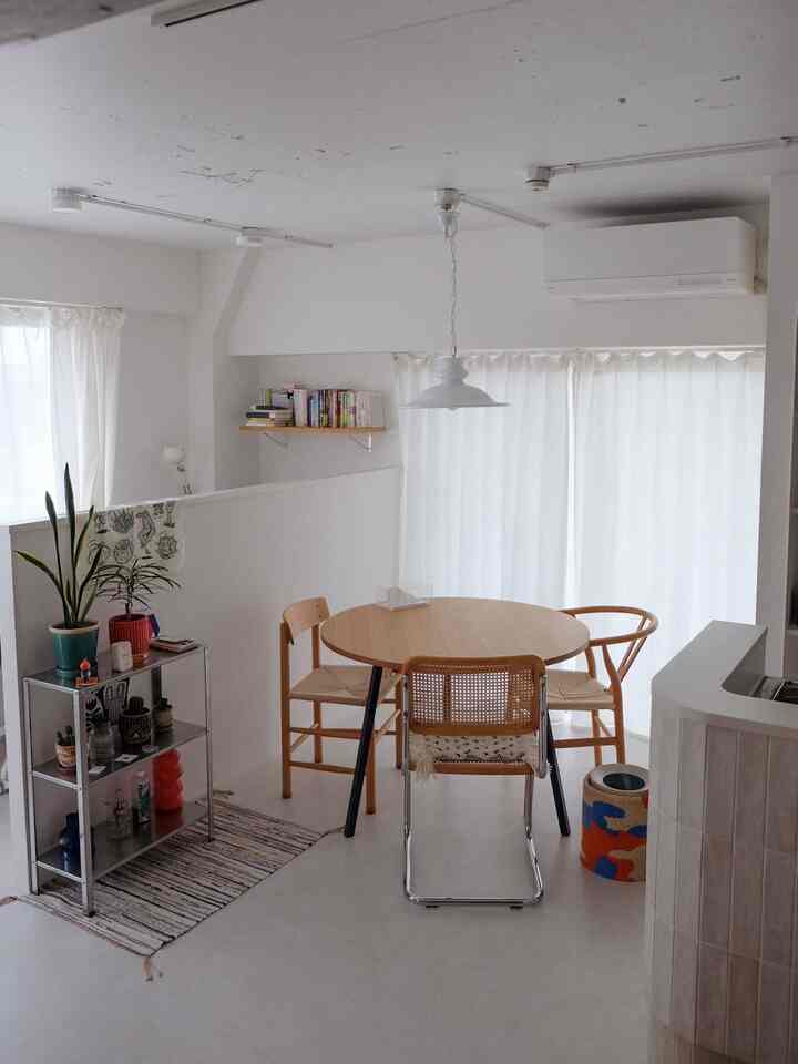 白と木目調の色調のダイニング、シンプルで北欧風の円形ダイニングテーブルと椅子が配置された雰囲気のある空間