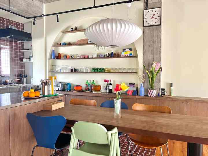 温かみのある木目調とミッドセンチュリーモダンスタイルのダイニングルーム、中央にダイニングチェアとペンダントライトが配された印象的な空間