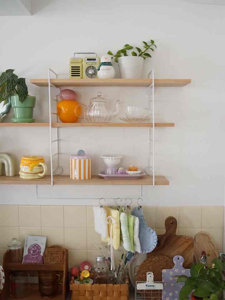 ナチュラルな木目調の棚にカラフルなキッチン用品が配置された雰囲気のあるキッチンスペース