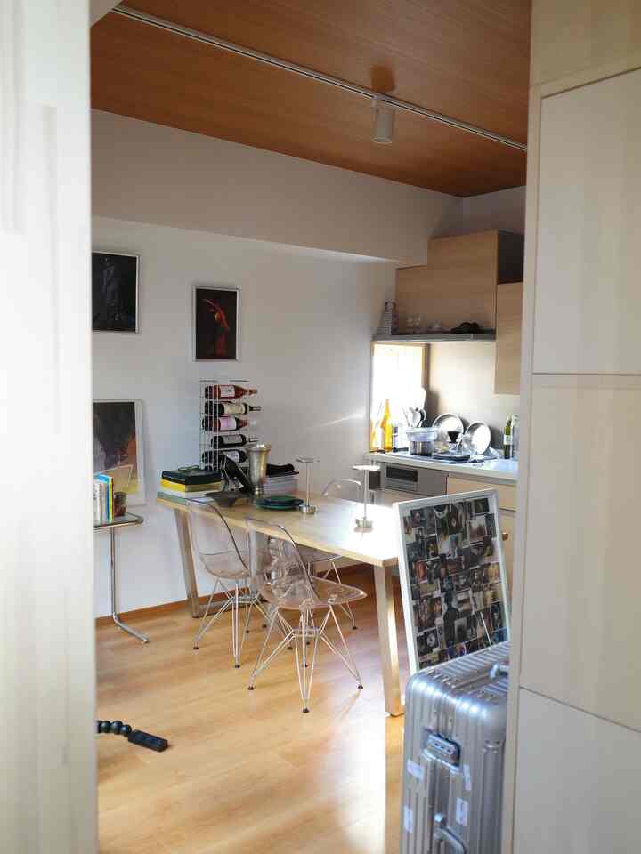 ナチュラルな木目調の1LDKキッチンとダイニング、透明な椅子が配置された温かみのあるインテリア