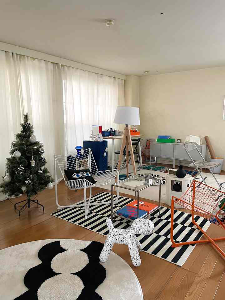 白と木目調が調和したミッドセンチュリーモダンのリビング、犬のオブジェと多様なデザイナーズ家具が配置された明るく居心地の良い空間