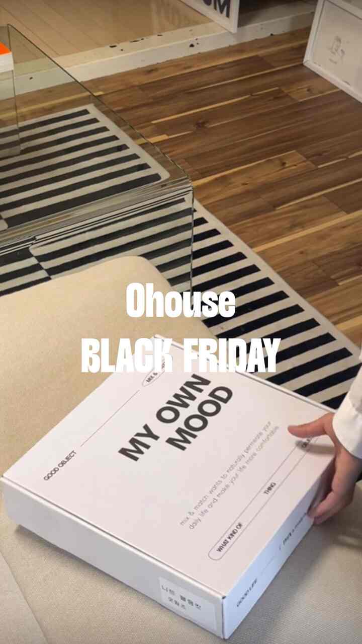 ベージュのソファの上にニットのブランケットボックスと黒のストライプリグがある、木目調のリビングスペース